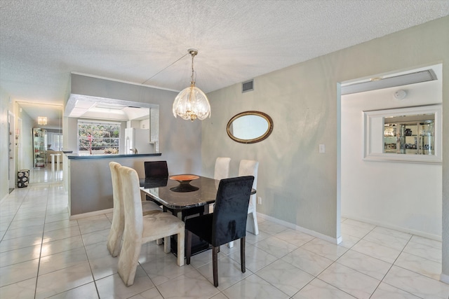dining space featuring visible vents, a textured ceiling, baseboards, and a chandelier