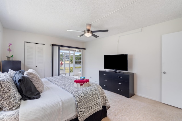bedroom featuring a ceiling fan, a textured ceiling, light carpet, and a closet