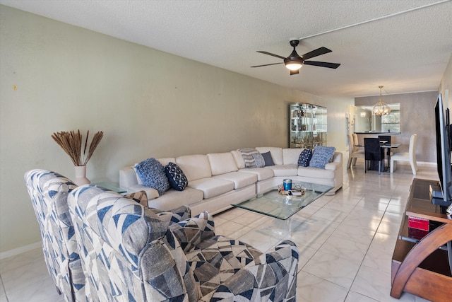 living room with ceiling fan with notable chandelier, a textured ceiling, and marble finish floor