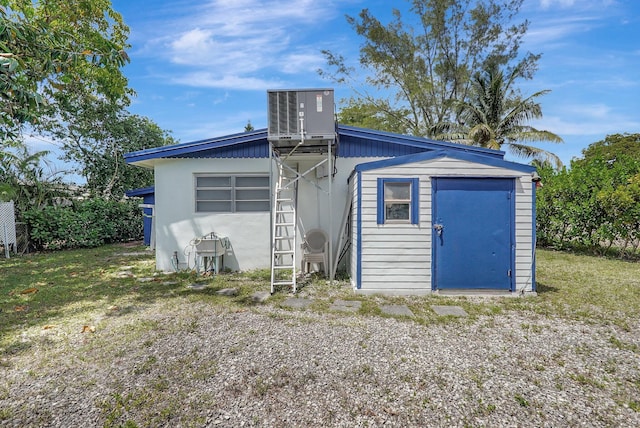 back of property featuring a storage unit, central air condition unit, and an outbuilding