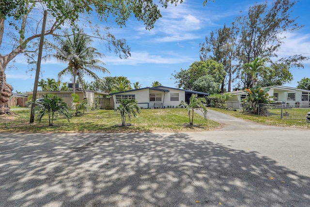 view of front of house with stucco siding, a front lawn, fence, and driveway