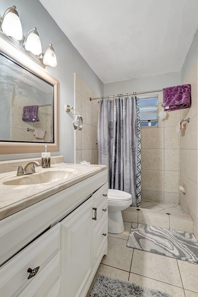 full bath with vanity, tile patterned flooring, toilet, and tiled shower