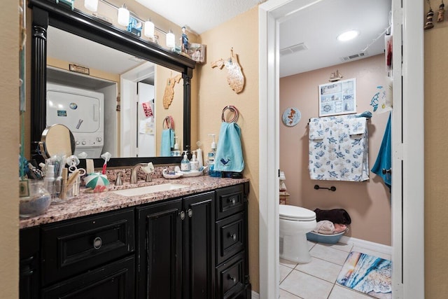 1627 SE Green Acres Cir Unit Z-203, Port Saint Lucie, FL 34952 - bathroom featuring stacked washer and dryer, visible vents, vanity, tile patterned floors, and toilet