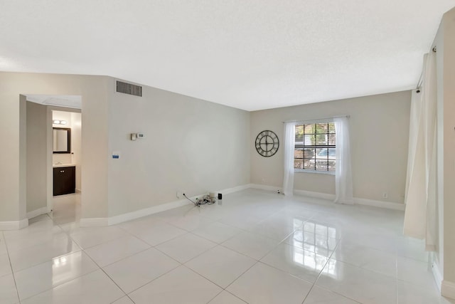 empty room featuring baseboards, visible vents, and light tile patterned floors