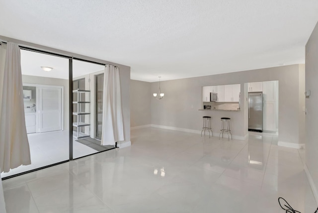 unfurnished room with a textured ceiling, baseboards, and light tile patterned floors