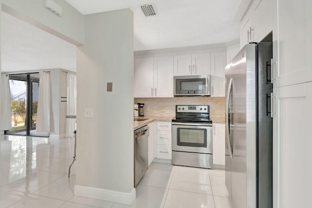kitchen with baseboards, decorative backsplash, light tile patterned flooring, and stainless steel appliances