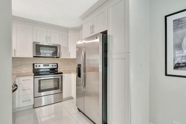 kitchen with light stone counters, appliances with stainless steel finishes, backsplash, and white cabinets