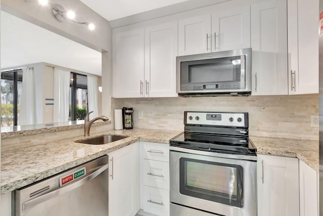 kitchen with white cabinets, appliances with stainless steel finishes, a wealth of natural light, and a sink