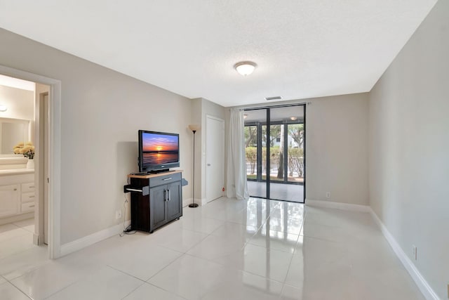unfurnished living room with baseboards, a textured ceiling, light tile patterned flooring, and visible vents