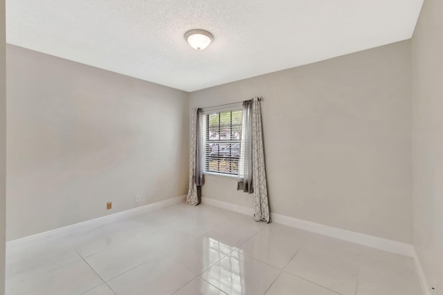 unfurnished room with tile patterned floors, baseboards, and a textured ceiling