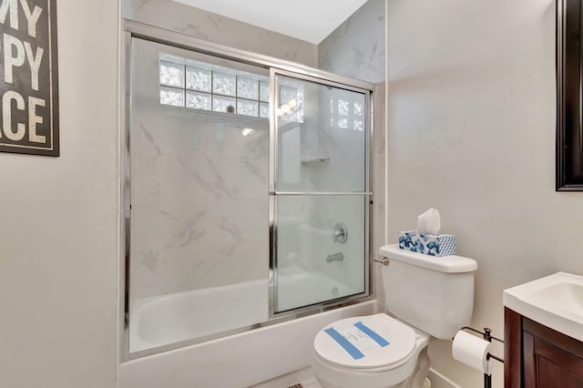 full bathroom featuring vanity, bath / shower combo with glass door, and toilet