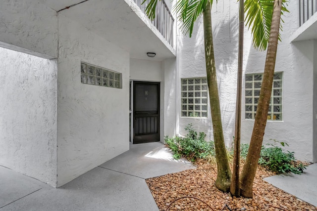 view of exterior entry with stucco siding and a balcony