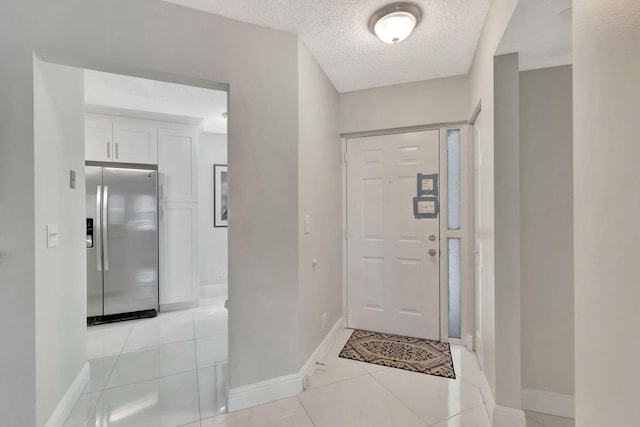 entrance foyer featuring light tile patterned floors, a textured ceiling, and baseboards