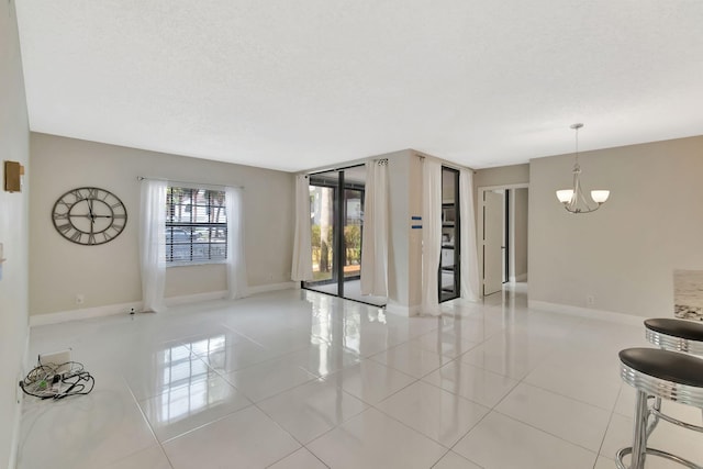 unfurnished living room featuring a textured ceiling, tile patterned floors, a notable chandelier, and baseboards