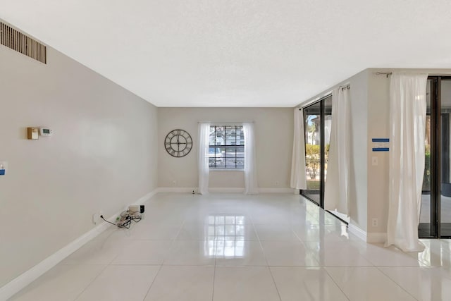 unfurnished room featuring baseboards, visible vents, and light tile patterned floors