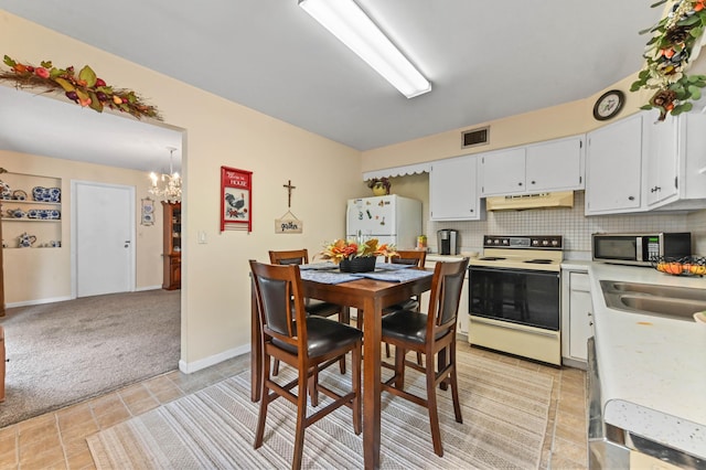 2104 S 26th St, Fort Pierce, FL 34947 - dining area featuring a chandelier, light colored carpet, light tile patterned floors, and baseboards
