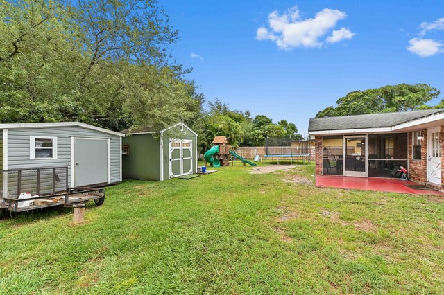 2104 S 26th St, Fort Pierce, FL 34947 - view of yard featuring a storage shed, a trampoline, a sunroom, a playground, and an outdoor structure