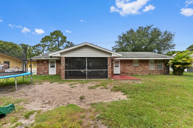 2104 S 26th St, Fort Pierce, FL 34947 - rear view of house featuring a trampoline, a sunroom, brick siding, and a yard