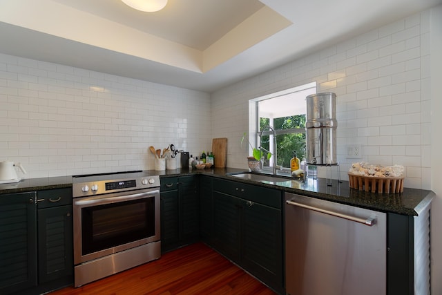 kitchen featuring backsplash, appliances with stainless steel finishes, a sink, and dark stone counters
