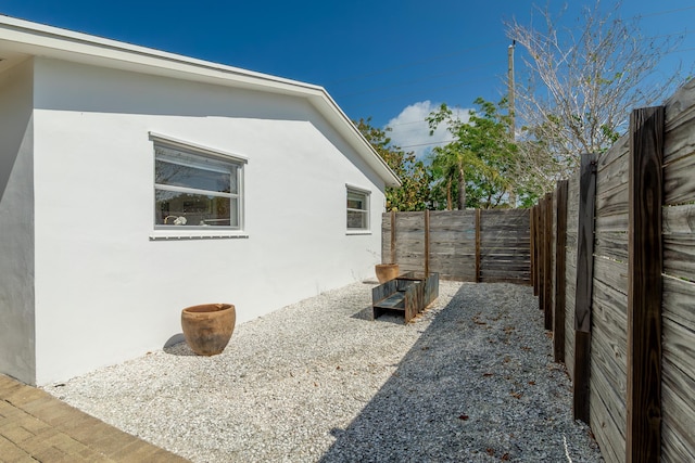 view of side of property featuring a fenced backyard and stucco siding
