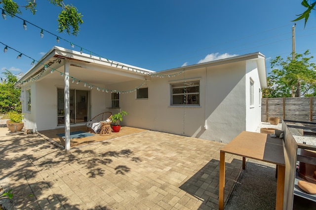 rear view of property with a patio, fence, and stucco siding