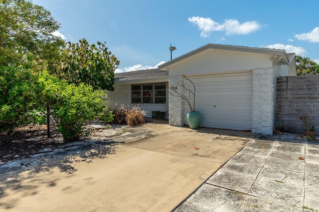 exterior space featuring an attached garage, fence, and stucco siding