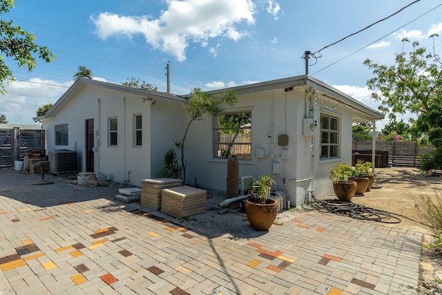 rear view of property with stucco siding, a patio area, central AC, and fence