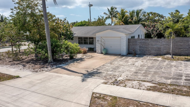 view of front of home with stucco siding, a garage, fence, and driveway