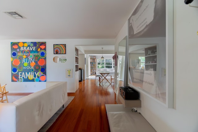 corridor with visible vents, baseboards, and wood finished floors