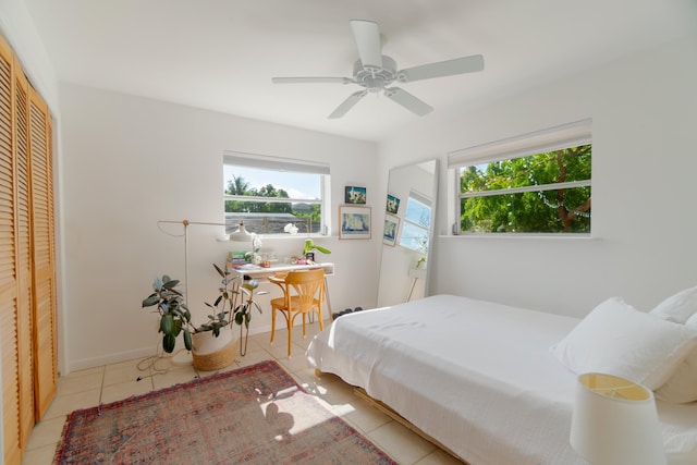 bedroom featuring baseboards, ceiling fan, a closet, and light tile patterned flooring