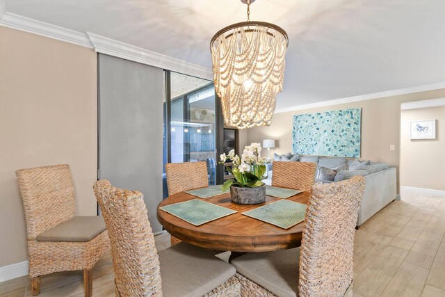 dining space featuring baseboards, ornamental molding, wood finished floors, and a notable chandelier