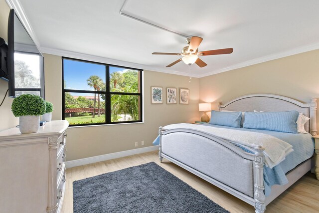 bedroom featuring baseboards, ornamental molding, light wood finished floors, and a ceiling fan