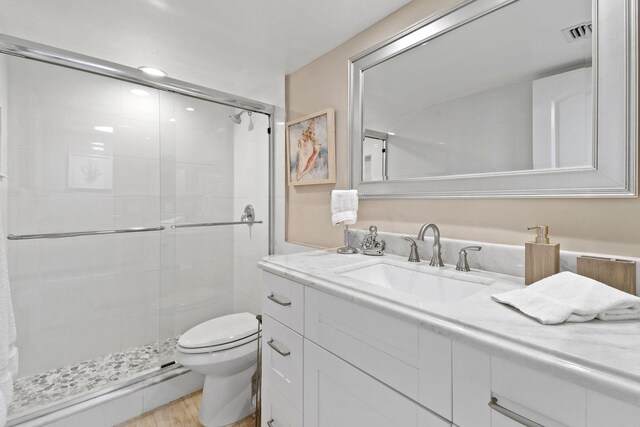 full bathroom with vanity, a shower stall, toilet, and visible vents