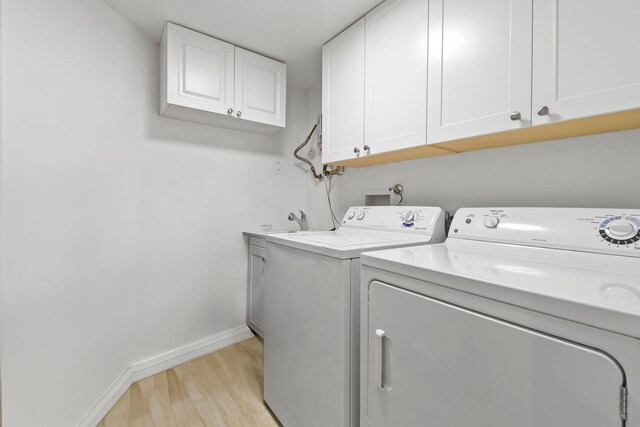 laundry area with baseboards, cabinet space, light wood finished floors, and washer and dryer
