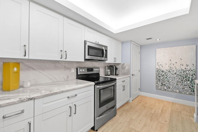 kitchen featuring tasteful backsplash, baseboards, white cabinets, light wood finished floors, and stainless steel appliances