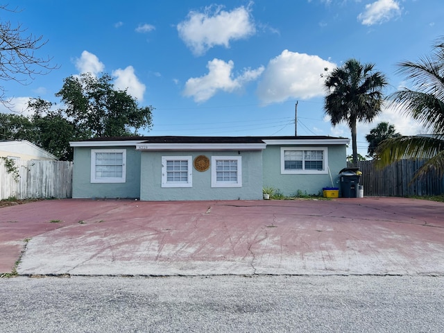 view of front of home with fence, stucco siding, and driveway