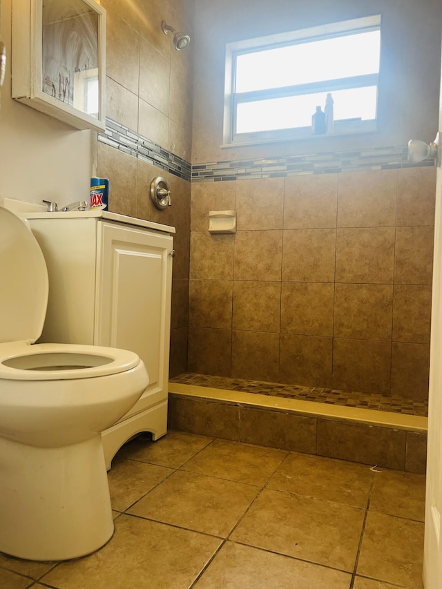 bathroom featuring toilet, a tile shower, and tile patterned flooring