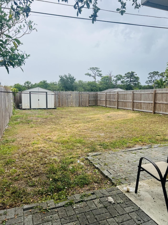 view of yard featuring a storage shed, an outbuilding, and a fenced backyard
