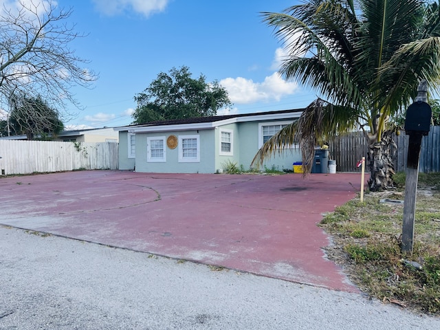 view of front of home with concrete driveway, fence, and stucco siding