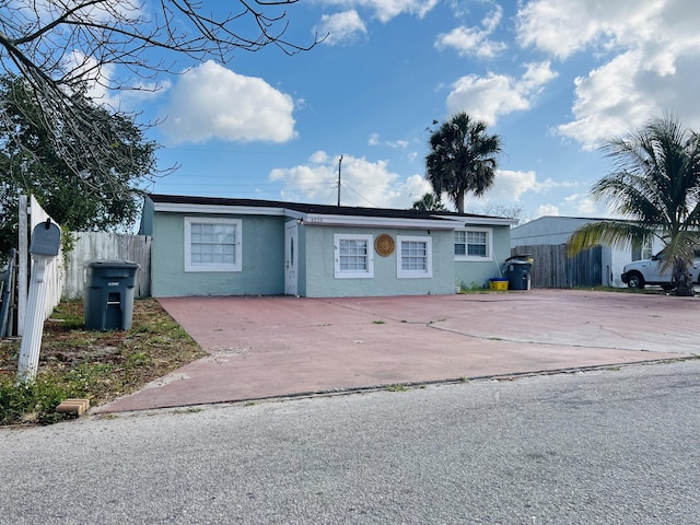 single story home with concrete driveway, stucco siding, and fence
