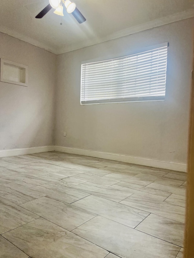 spare room with a ceiling fan and baseboards