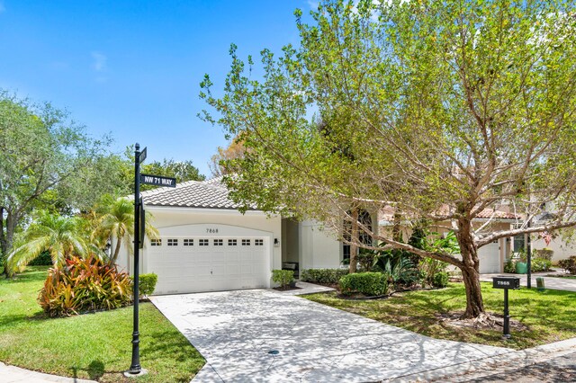 obstructed view of property featuring driveway, a tile roof, a garage, a front lawn, and stucco siding