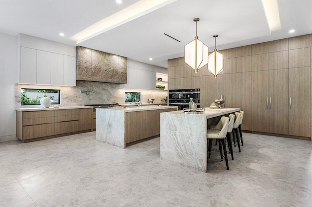 217 Thatch Palm Dr, Boca Raton, FL 33432 - kitchen featuring modern cabinets, an island with sink, tasteful backsplash, pendant lighting, and a sink