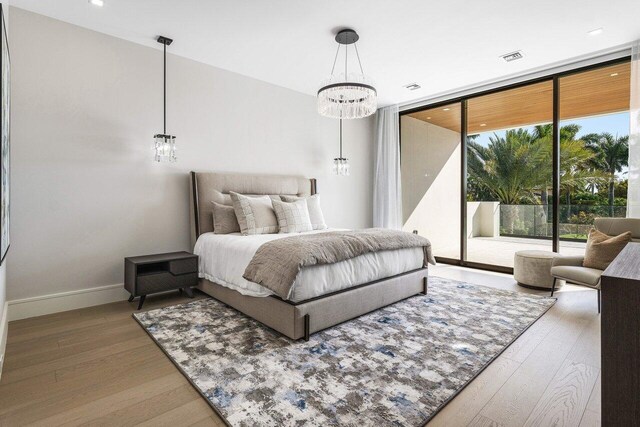 217 Thatch Palm Dr, Boca Raton, FL 33432 - bedroom featuring a chandelier, access to exterior, wood finished floors, baseboards, and a wall of windows