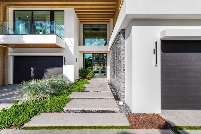 217 Thatch Palm Dr, Boca Raton, FL 33432 - property entrance featuring stucco siding, a garage, stone siding, french doors, and a balcony
