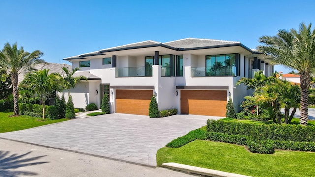 2498 Queen Palm Rd, Boca Raton, FL 33432 - view of front of house featuring stucco siding, a balcony, a garage, and driveway