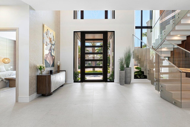 entryway with stairway, a high ceiling, and baseboards