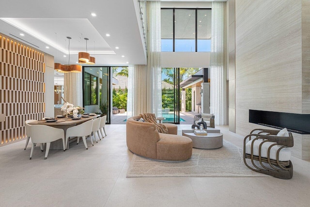 living area with a towering ceiling, recessed lighting, plenty of natural light, and a tray ceiling
