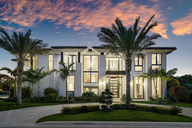 property at dusk featuring curved driveway