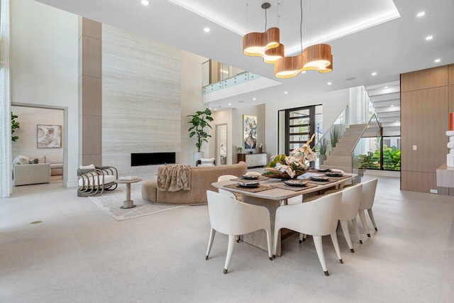 dining room featuring a high ceiling, recessed lighting, a high end fireplace, and stairs
